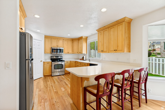 298 North Canyon Road Bountiful, UT 84010 - Photo 17 of 57 Spacious kitchen featuring wood-finish flooring, light-toned cabinetry with crown molding, stainless steel appliances, a white countertop, and recessed lighting