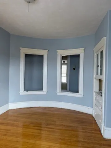 a view of an empty room with window and wooden floor