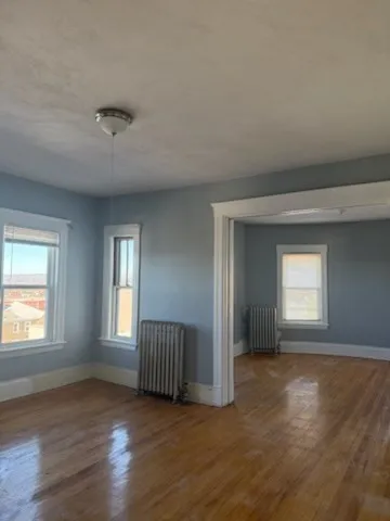 a view of empty room with window and wooden floor
