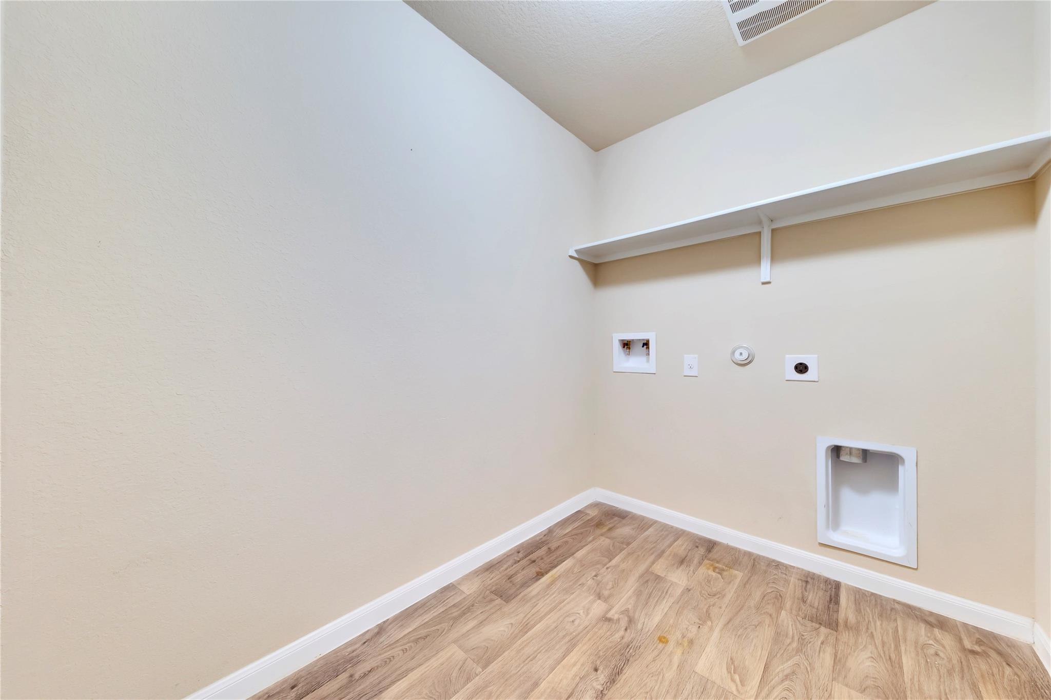 5913 Diamondleaf Bend Austin, TX 78724 - Photo 15 of 20 Dedicated utility space featuring light wood-finish flooring, light-toned walls, a built-in wall shelf, and essential appliance hookups