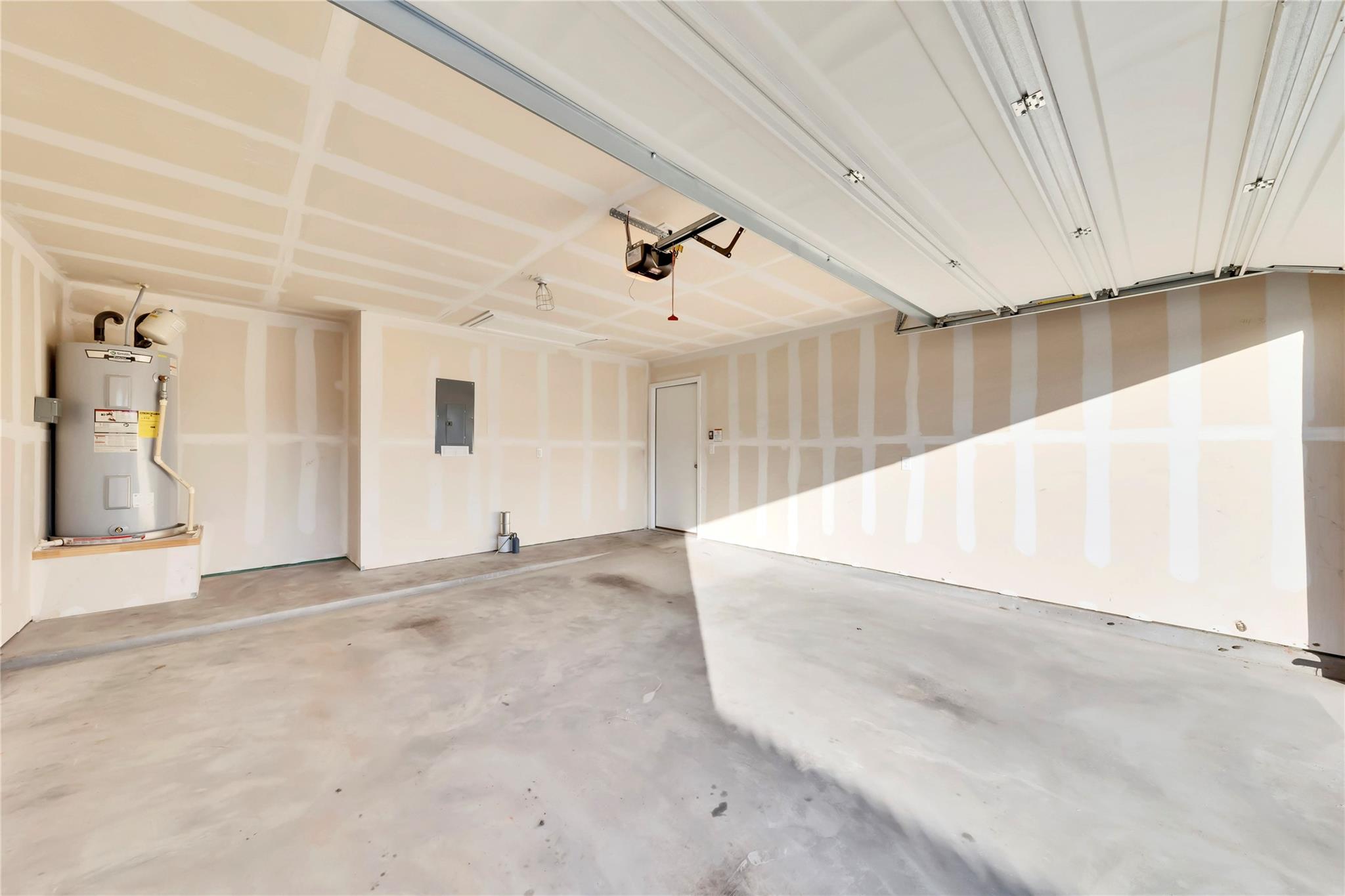 5913 Diamondleaf Bend Austin, TX 78724 - Photo 16 of 20 Attached two-car garage featuring a concrete floor, exposed ceiling joists, partially finished drywall, and a functional water heater