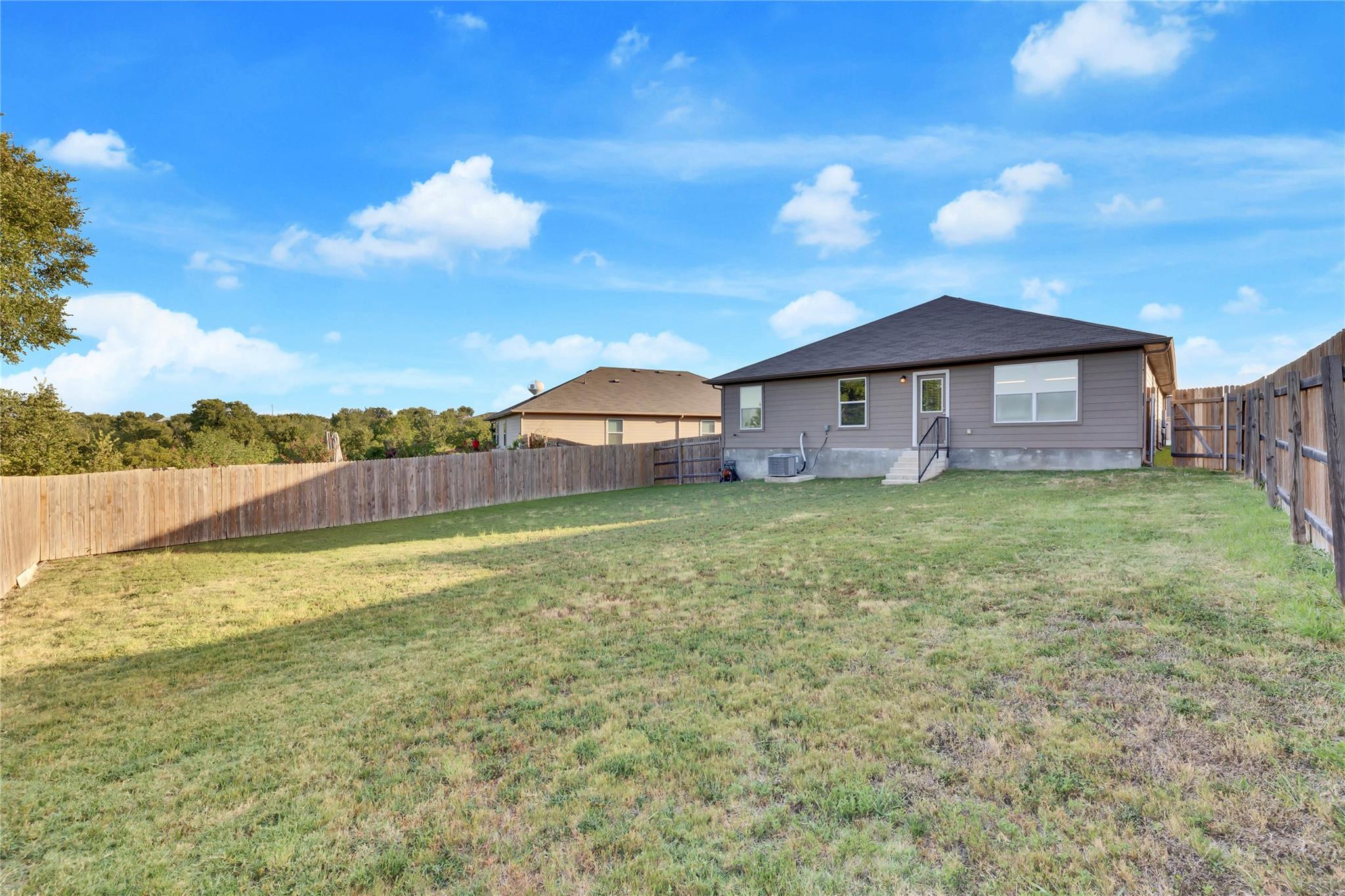 5913 Diamondleaf Bend Austin, TX 78724 - Photo 20 of 20 Expansive backyard featuring a manicured lawn, full perimeter wood fencing, and a rear exterior with a pitched roof