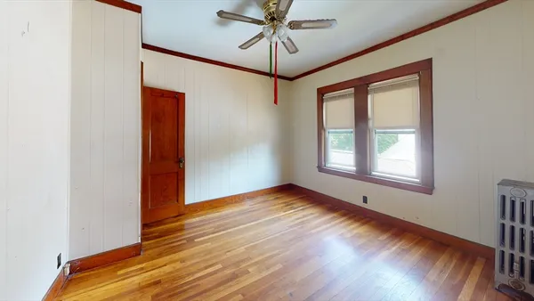 a view of an empty room with window and wooden floor