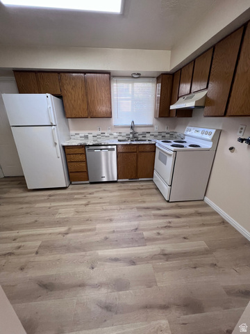 556 North Fairfield Road, Unit D4 Layton, UT 84041 - Photo 3 of 23 Kitchen featuring white appliances, light countertops, light wood finished floors, under cabinet range hood, and brown cabinetry
