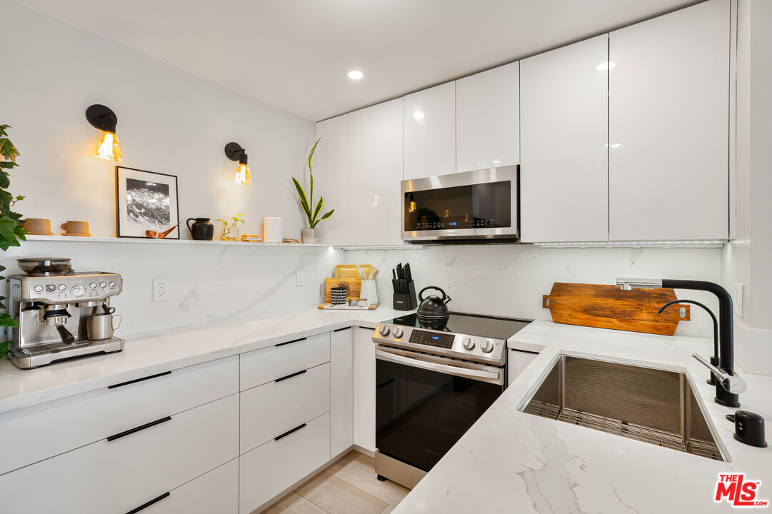 11750 Sunset Boulevard, Unit 407 Los Angeles, CA 90049 - Photo 5 of 12 a kitchen with a sink a stove and cabinets