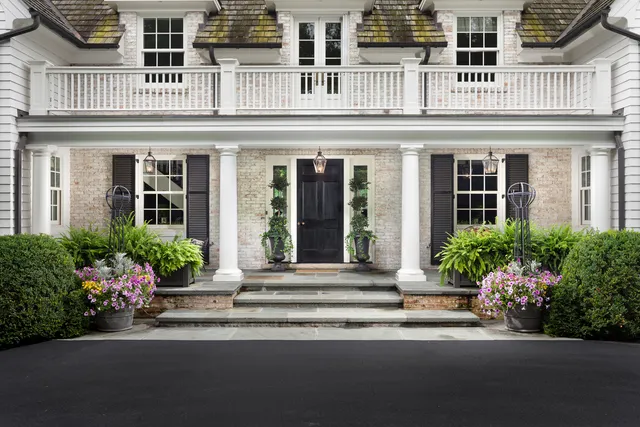 a view of a house with a big yard potted plants and large tree