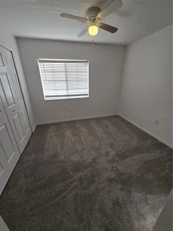 an empty room with windows and fan