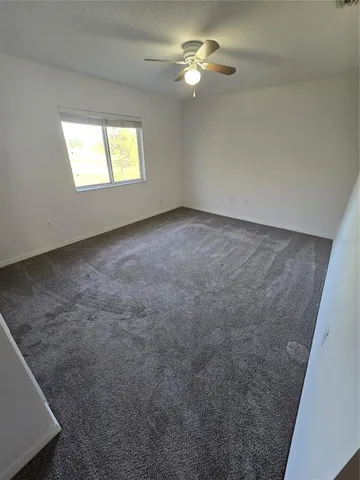 an empty room with windows and fan