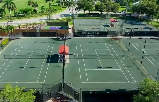 an aerial view of a tennis ground with a small yard and large trees