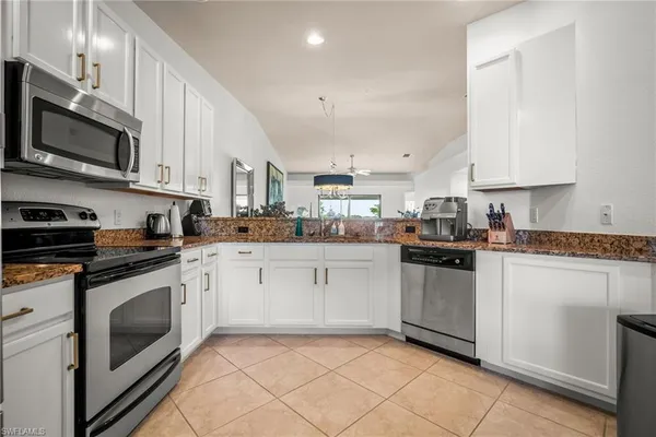 a kitchen with stainless steel appliances granite countertop a sink dishwasher stove and white cabinets with wooden floor