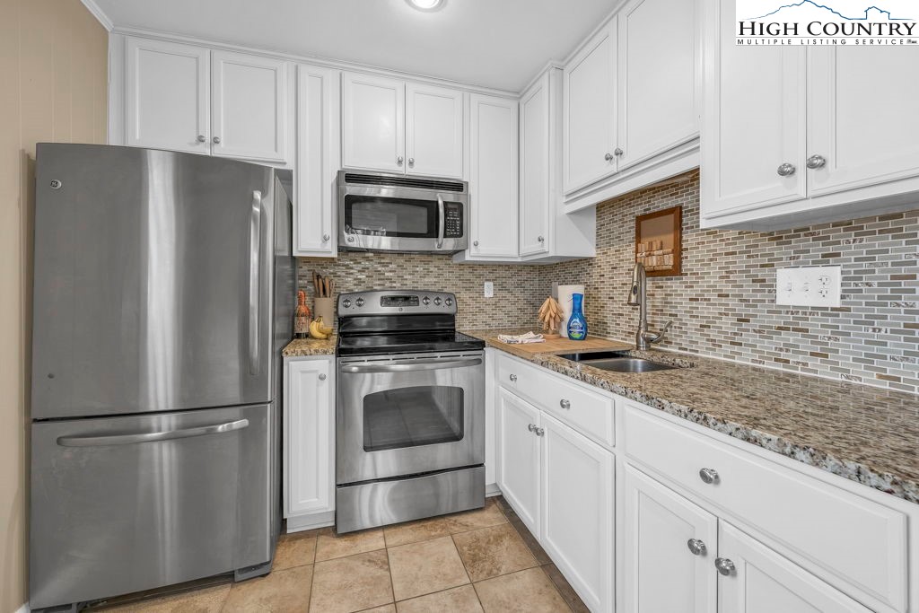 837 Pine Ridge Road Beech Mountain, NC 28604 - Photo 4 of 23 a kitchen with stainless steel appliances granite countertop a refrigerator a stove a sink and white cabinets
