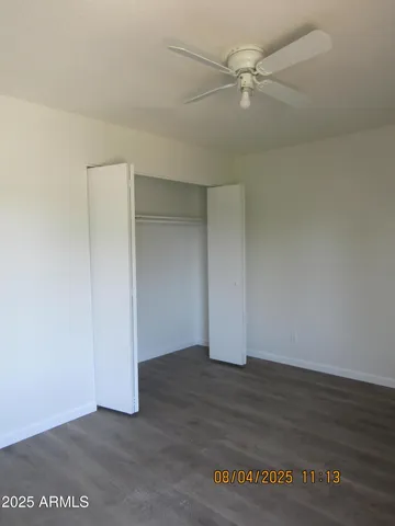 an empty room with wooden floor and fan