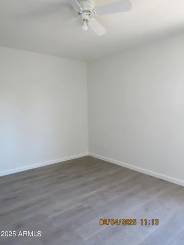 an empty room with wooden floor and fan