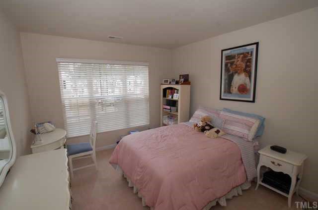 7038 Racine Way Raleigh, NC 27615 - Photo 11 of 12 a bedroom with a bed and wooden floor