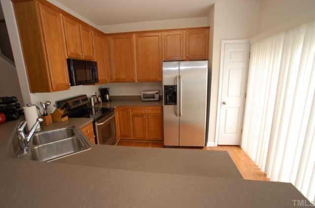 7038 Racine Way Raleigh, NC 27615 - Photo 4 of 12 a kitchen with a refrigerator and a stove top oven