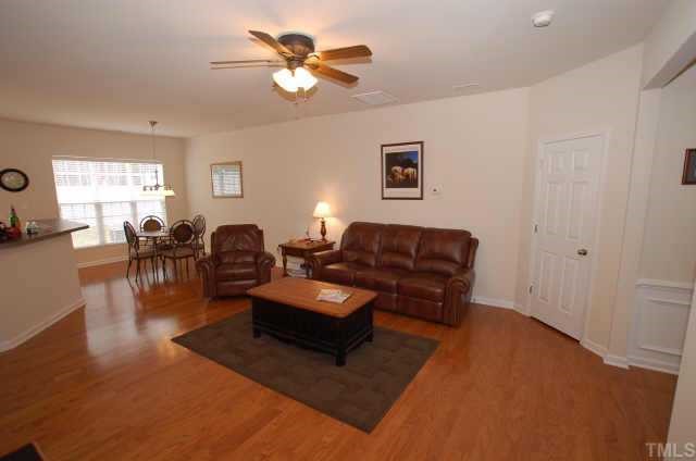 7038 Racine Way Raleigh, NC 27615 - Photo 12 of 12 a living room with couches and a potted plant on a coffee table and a window with wooden floor