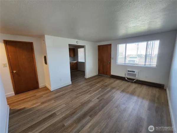 an empty room with wooden floor and windows