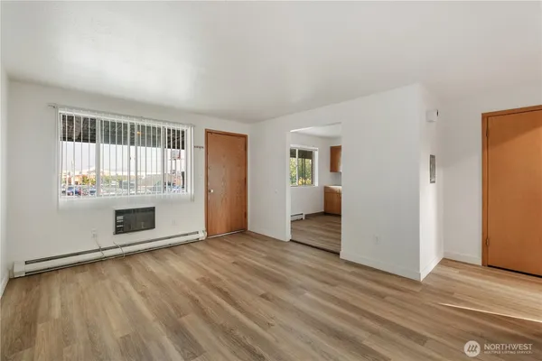 an empty room with wooden floor fireplace and windows