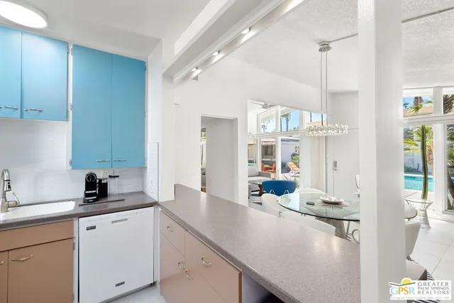 a kitchen with a sink dishwasher and white cabinets next to a window