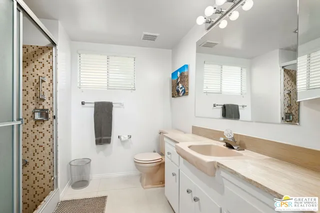 a spacious bathroom with a toilet a sink and a large mirror