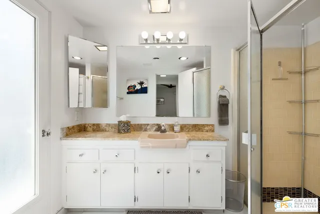 a bathroom with a granite countertop sink a mirror and a shower