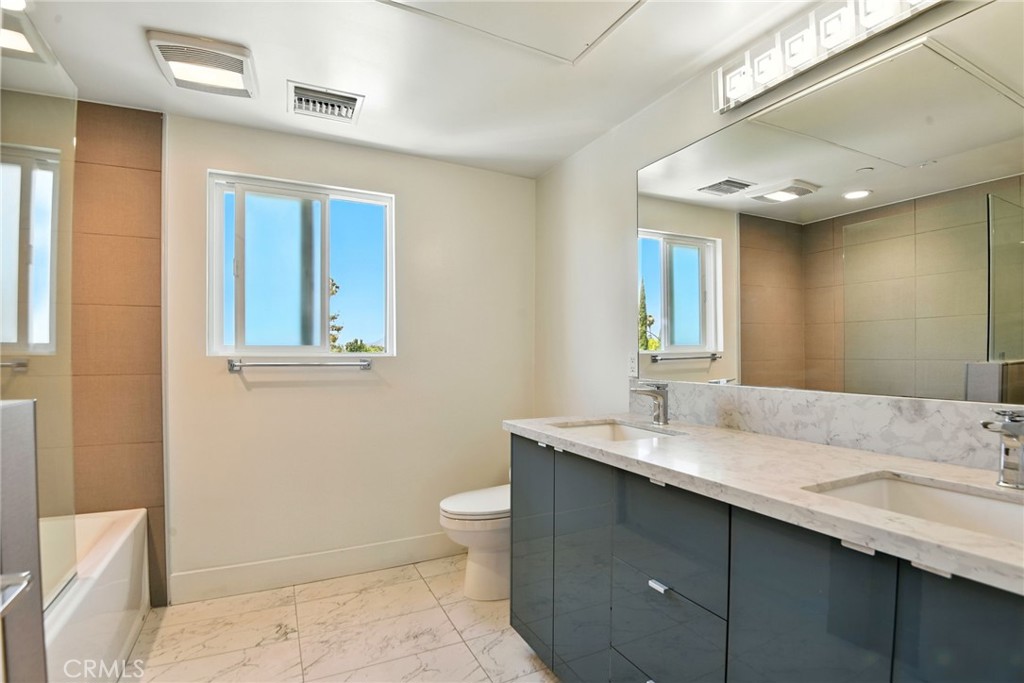 4461 Tujunga Avenue, Unit 101 Studio City, CA 91602 - Photo 27 of 34 a bathroom with a granite countertop sink a toilet and a mirror