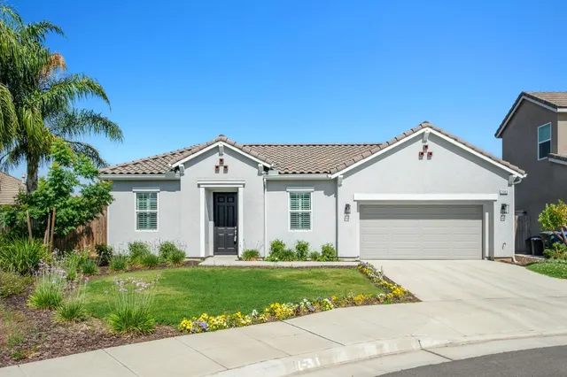 a view of a white house next to a yard and palm trees