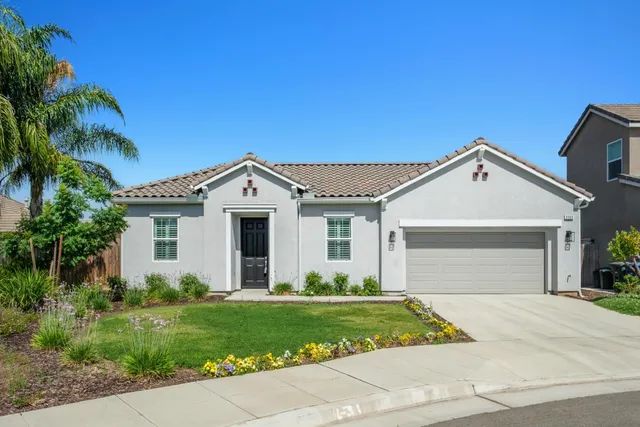a view of a white house next to a yard and palm trees