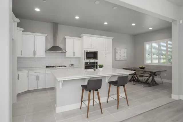 a kitchen with stainless steel appliances granite countertop a stove a sink a refrigerator and a microwave