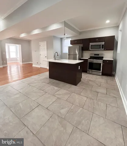 a large kitchen with kitchen island granite countertop a stove a sink a counter top space and cabinets