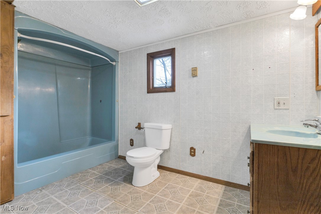 48265 Middle Ridge Road Amherst, OH 44001 - Photo 24 of 43 Large primary bathroom with vanity, toilet, tub/shower combo, built in storage and electric baseboard heater.