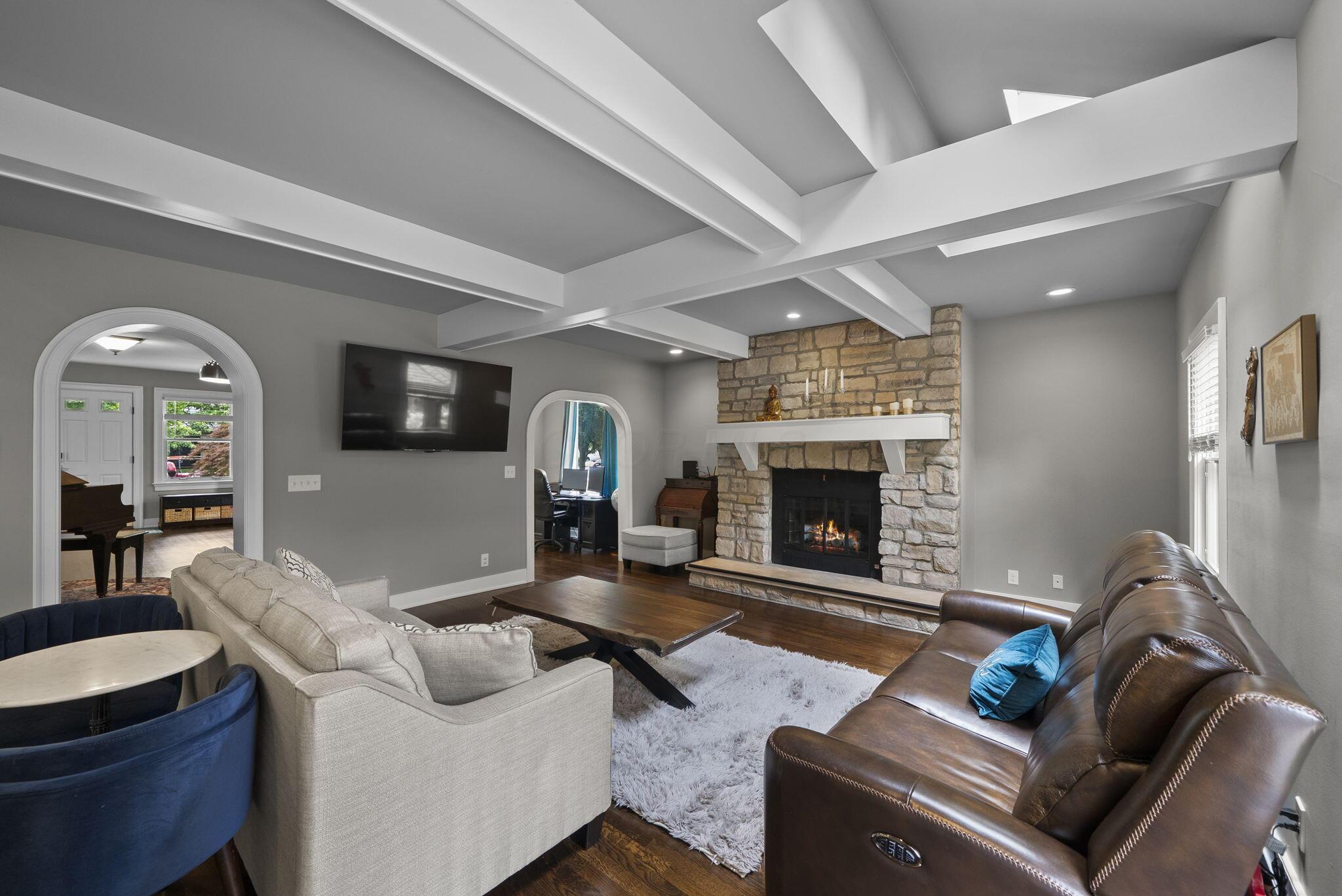 1851 Berkshire Road Columbus, OH 43221 - Photo 20 of 125 Step down family room with elevated coffered ceilings, warm gas fireplace and mantle with stone hearth, lit with skylights and architectural detail curved doorways.