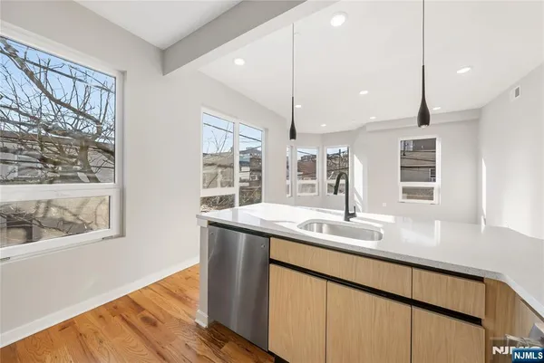 a kitchen with stainless steel appliances granite countertop a sink a window and wooden floor