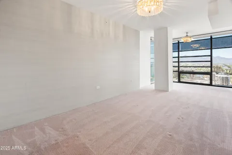 a view of an empty room with chandelier fan