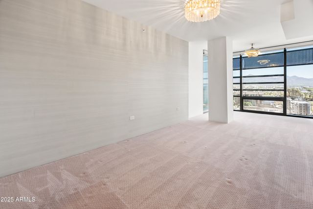 a view of an empty room with chandelier fan