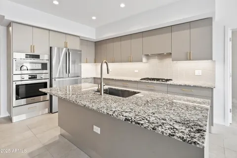 a kitchen with stainless steel appliances granite countertop a sink stove and refrigerator