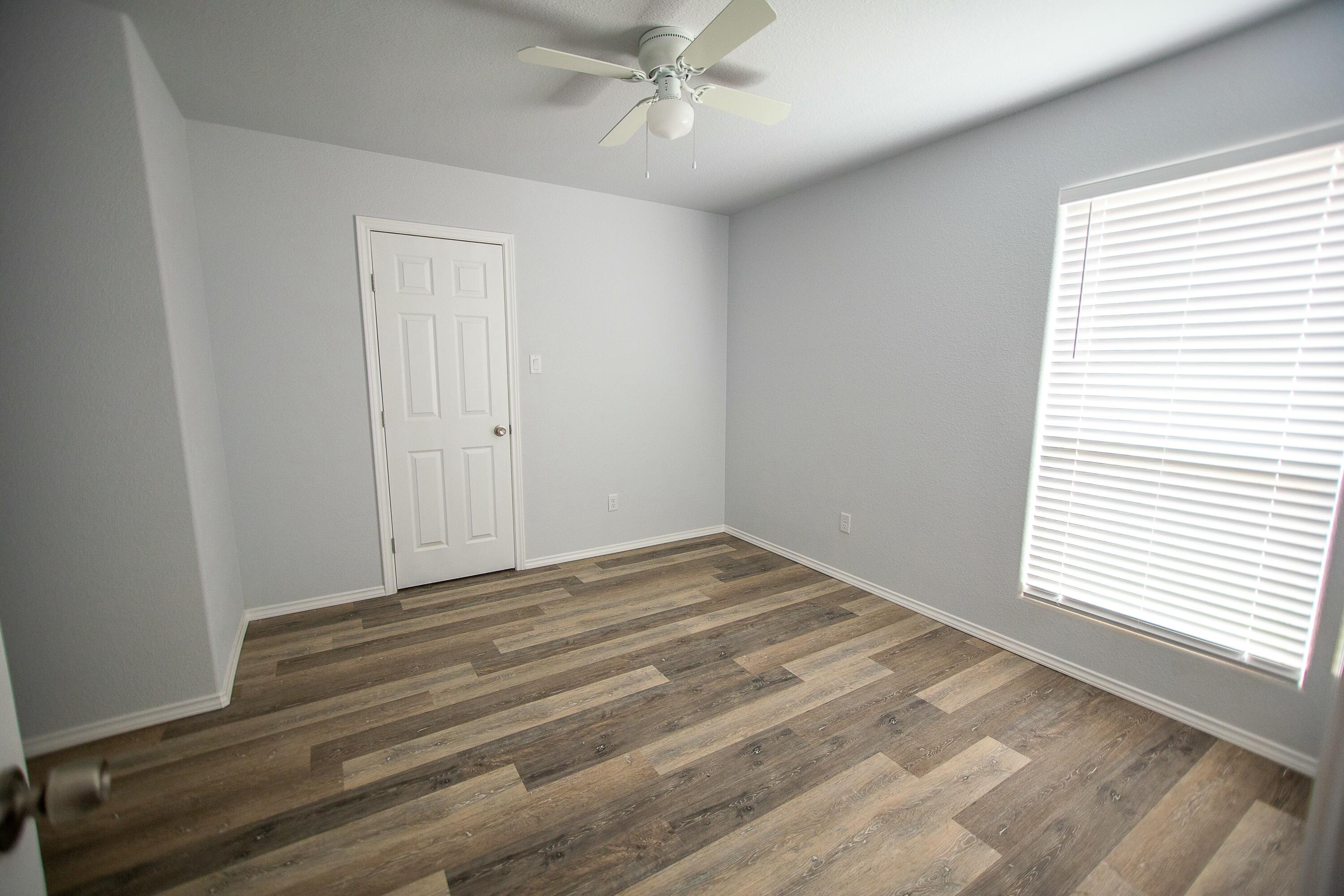 8613 10th Place Lubbock, TX 79416 - Photo 4 of 9 a view of empty room with wooden floor and fan