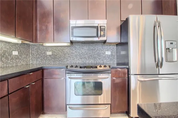 a kitchen with granite countertop a refrigerator stove and microwave