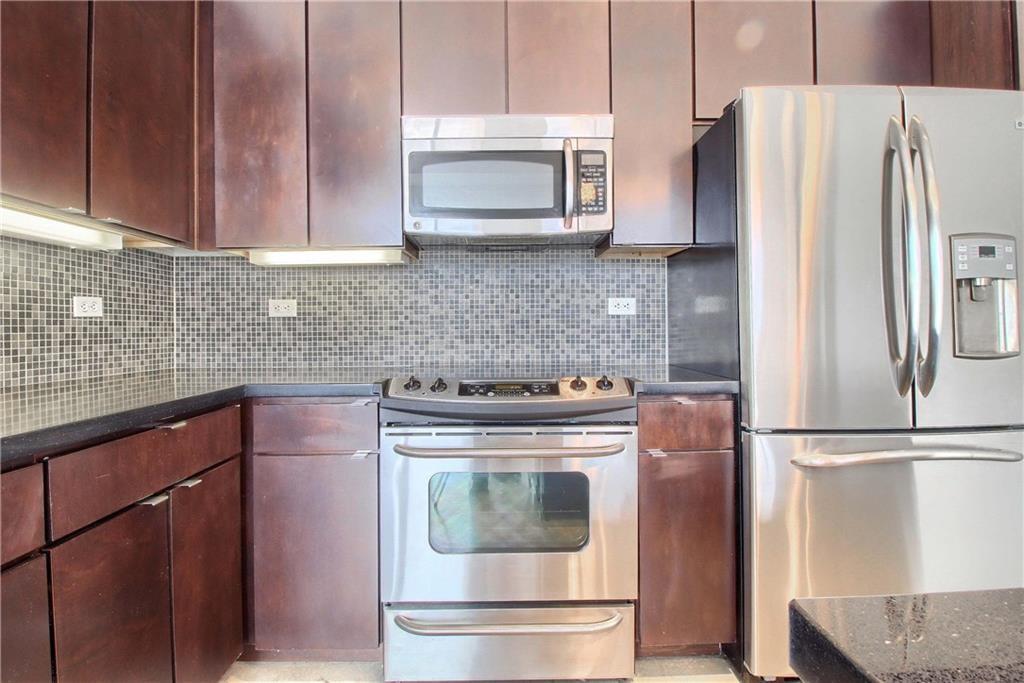 507 Sabine Street, Unit 602 Austin, TX 78701 - Photo 3 of 22 a kitchen with granite countertop a refrigerator stove and microwave