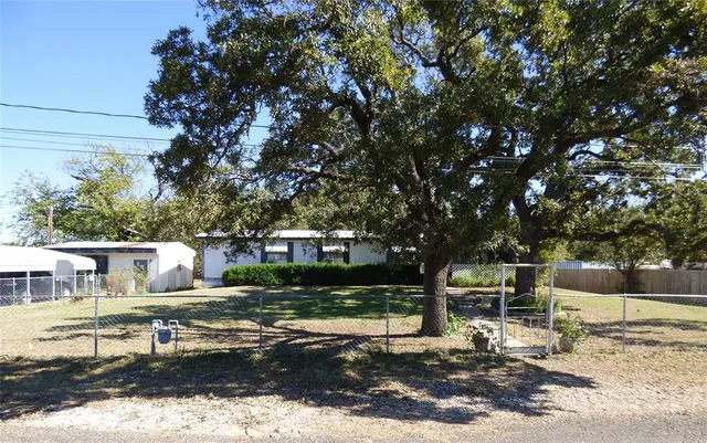 a view of house with yard outdoor seating and covered with trees
