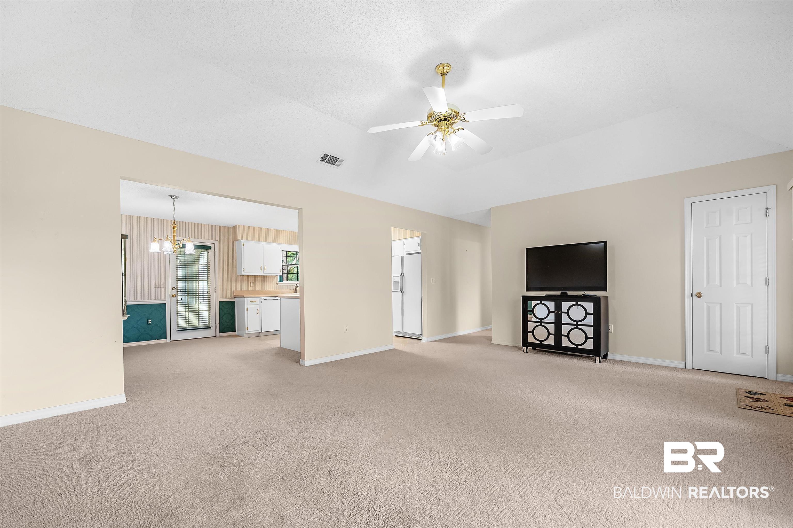 1502 Mulberry Lane Foley, AL 36535 - Photo 10 of 45 Unfurnished living room featuring ceiling fan with notable chandelier, light carpet, and a raised ceiling