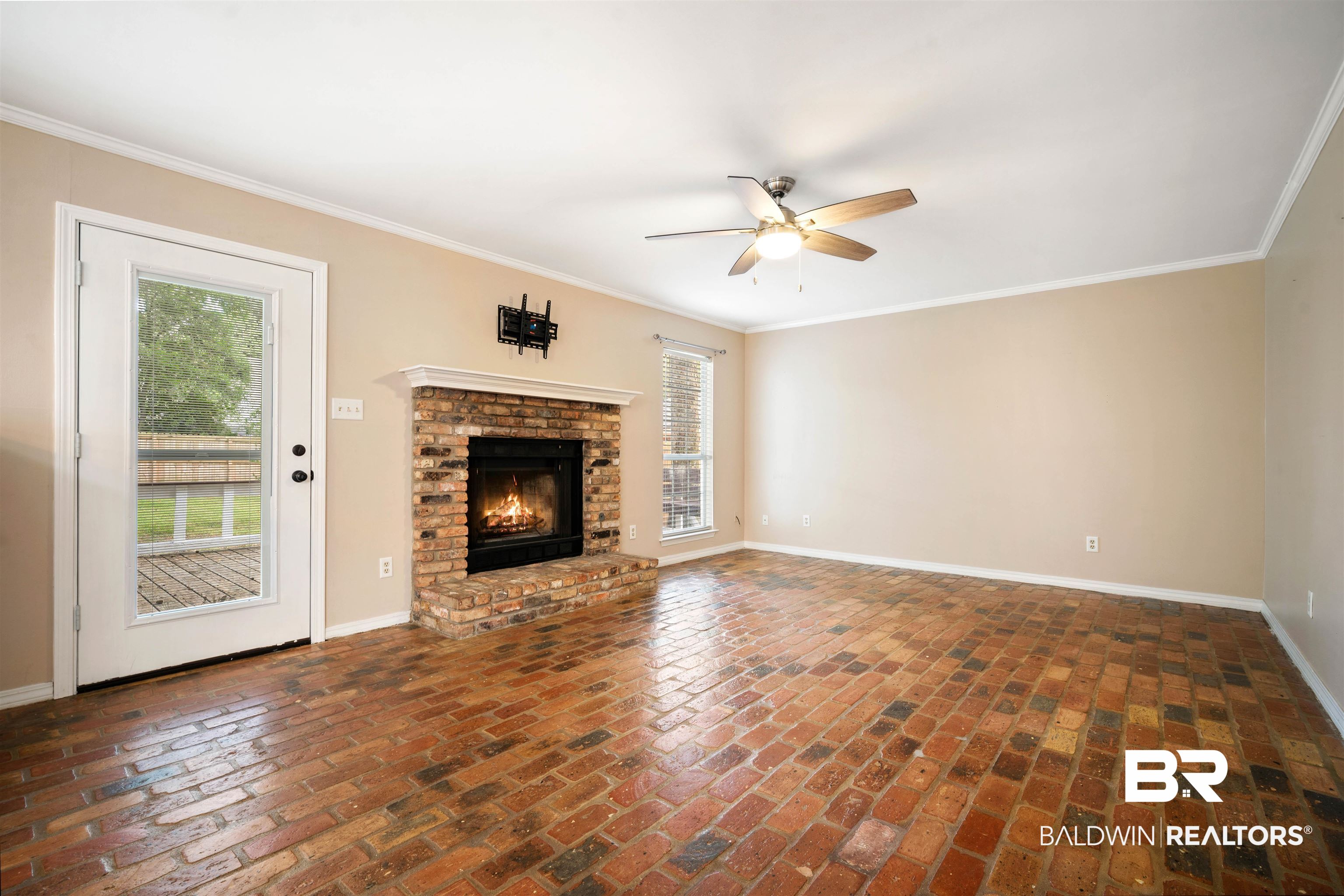 804 Wildwood Avenue Mobile, AL 36609 - Photo 5 of 30 Unfurnished living room featuring ceiling fan, ornamental molding, and a brick fireplace