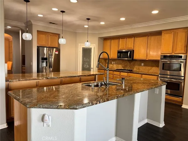 a kitchen with stainless steel appliances granite countertop a sink a stove and a refrigerator
