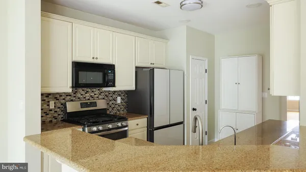 a kitchen with stainless steel appliances granite countertop a stove a refrigerator and a microwave