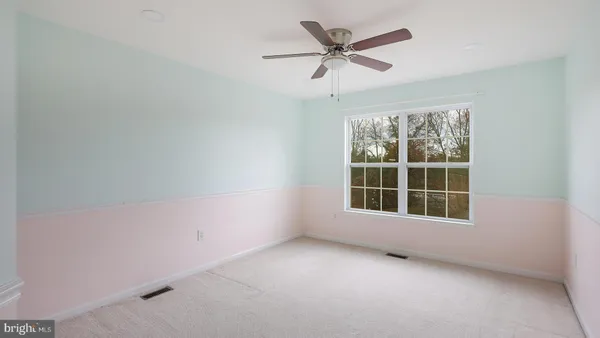 an empty room with a ceiling fan and windows