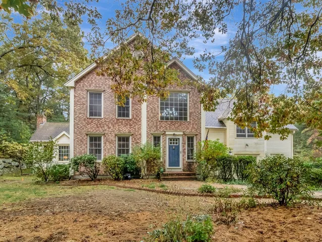a view of a white house next to a yard with plants and trees