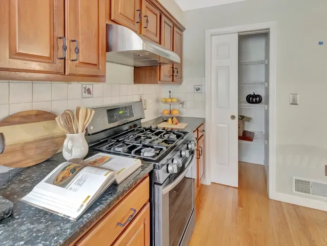 a kitchen with stainless steel appliances granite countertop a stove and a wooden cabinets