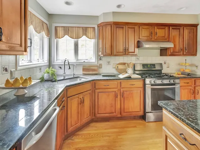a kitchen with stainless steel appliances granite countertop a sink stove and cabinets