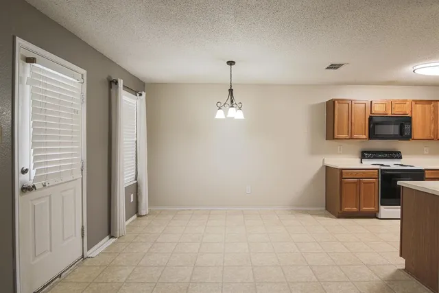 a kitchen with granite countertop a refrigerator and a stove top oven