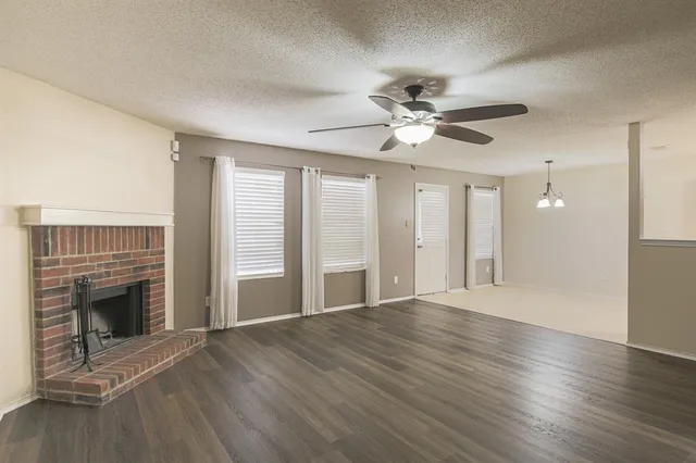 a view of an empty room with wooden floor and a fireplace